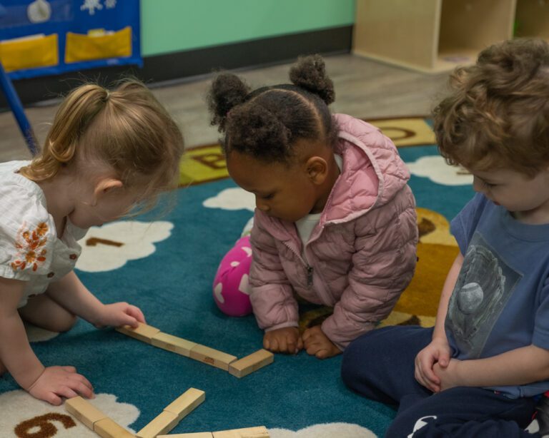 3 children playing with wooden blocks