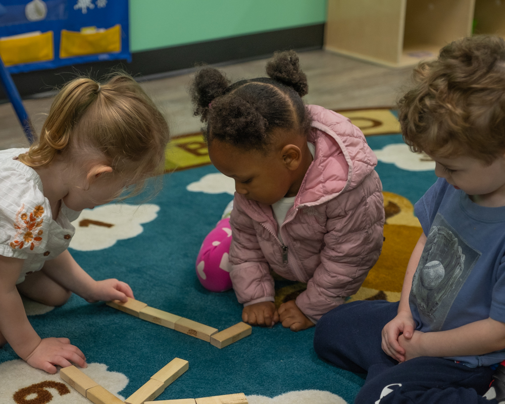 3 children playing with wooden blocks